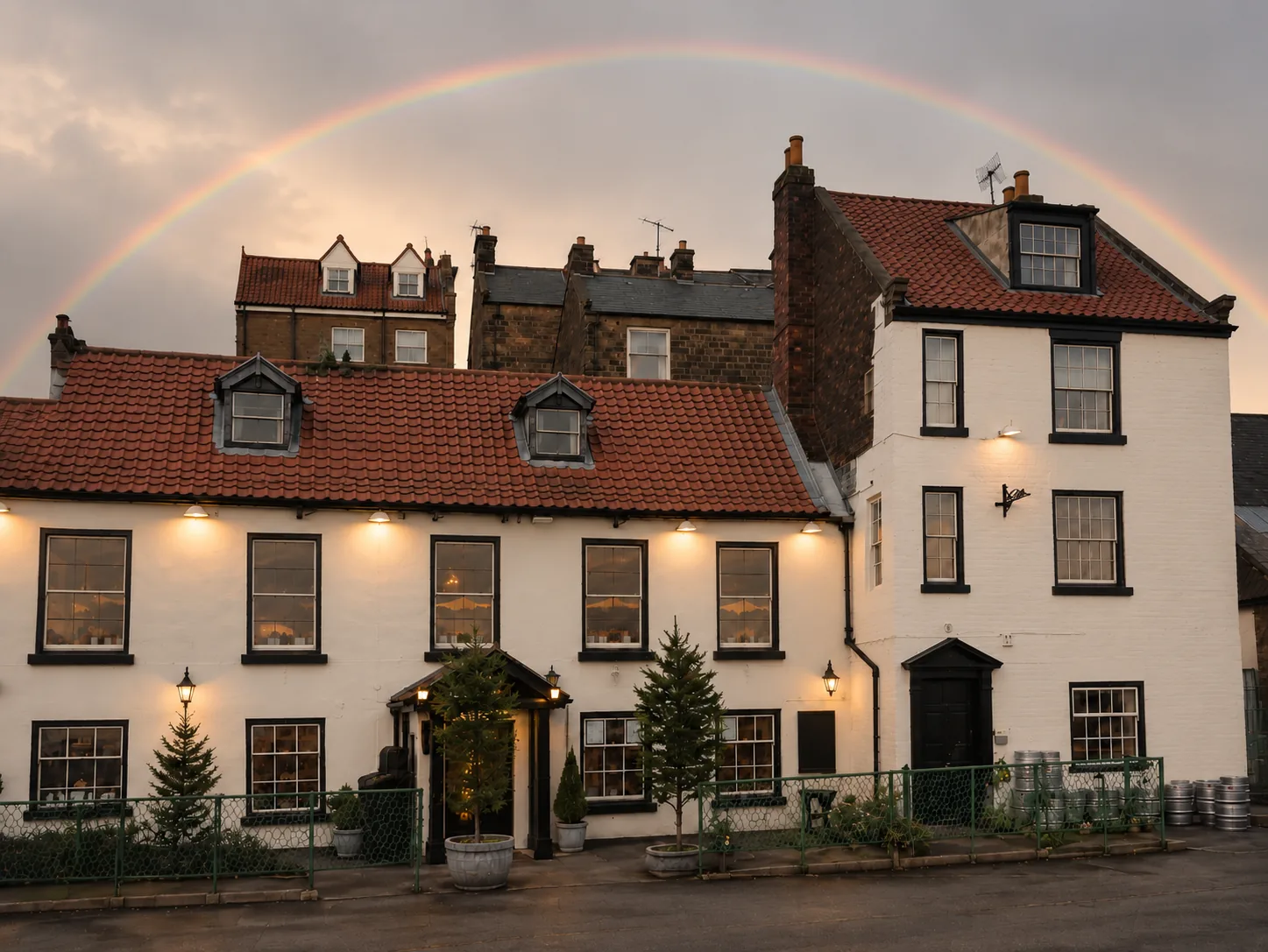 Middle Earth Tavern exterior at dusk with a rainbow arcing over the red-tiled roofs of old Whitby